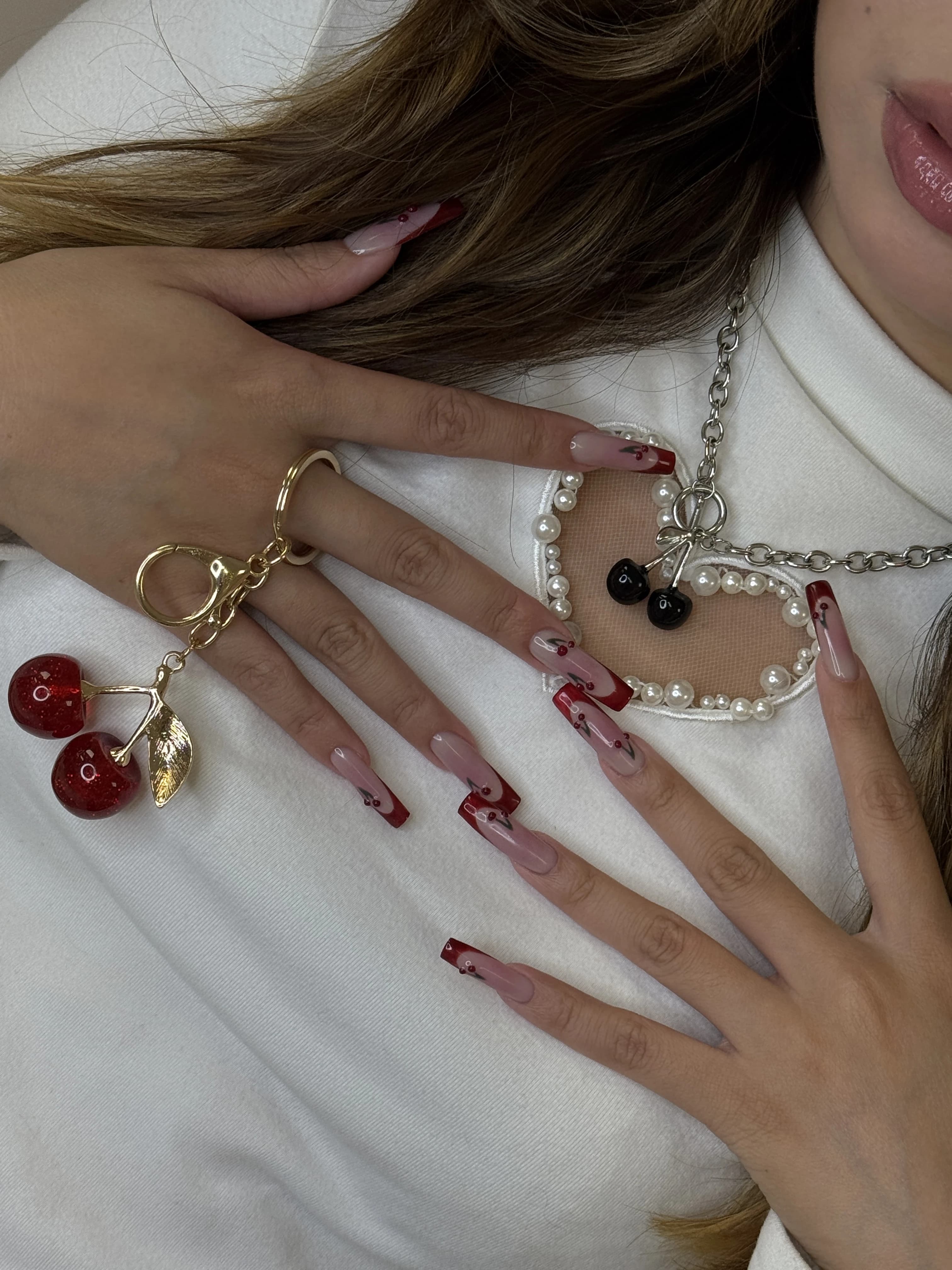 Mississauga hard gel coffin nails with nude bases, red French tips, cherry art, and a matching cherry keychain.