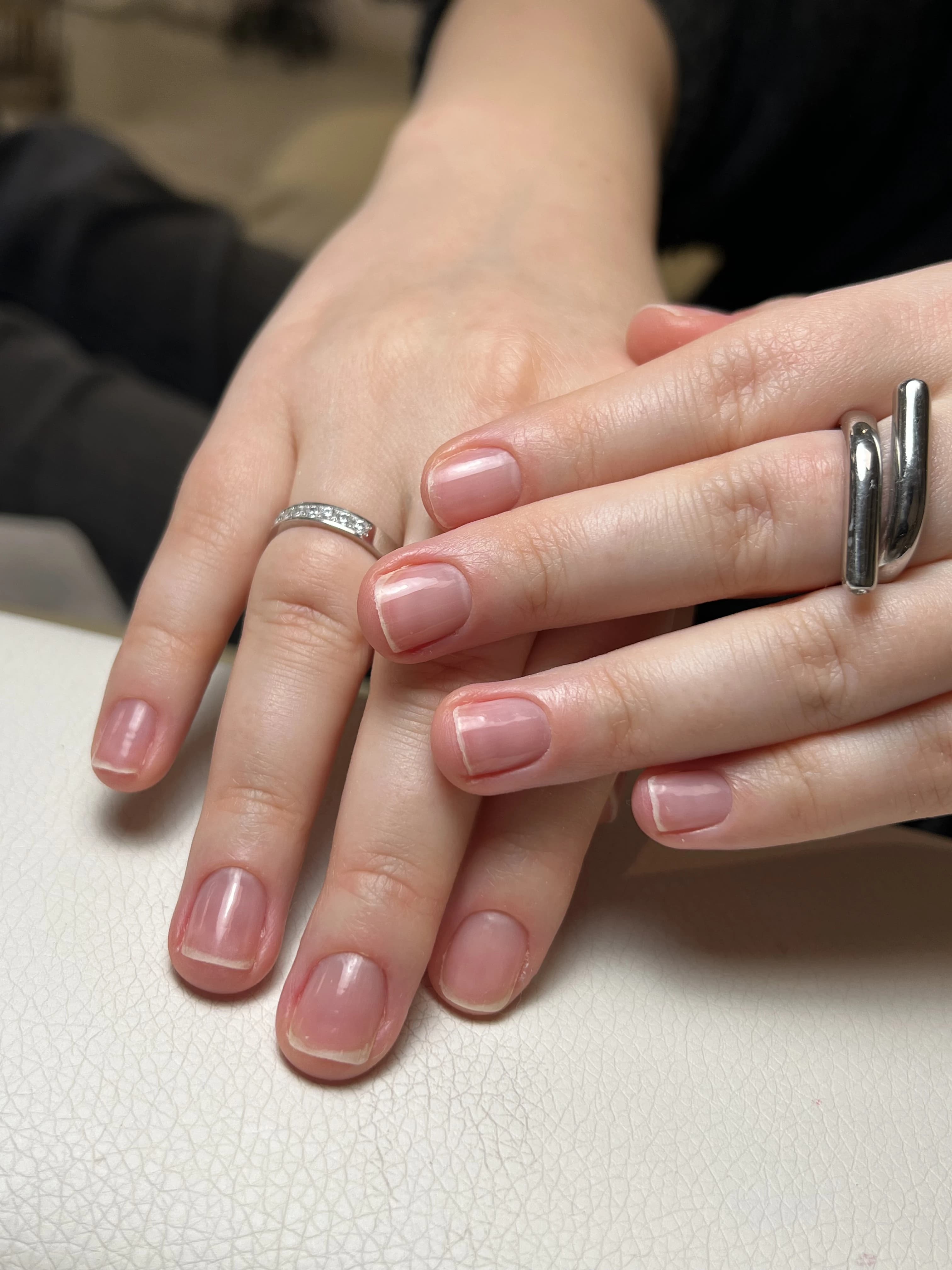 Japanese manicure at My Beauty Space: short squoval nails buffed to a mirror-clear shine, hands crossed on a white table.