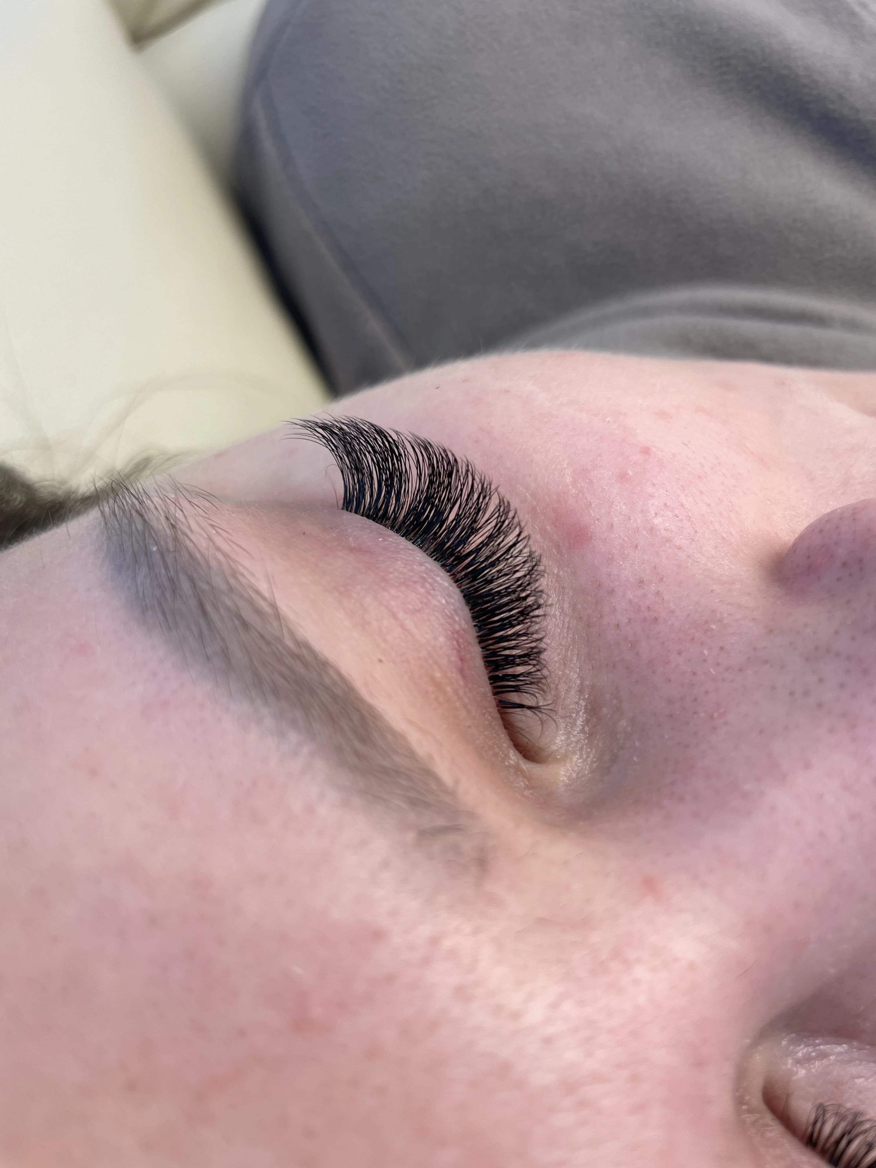 Light hybrid 2D lash extensions on a closed eye with a soft natural blonde brow at My Beauty Space.