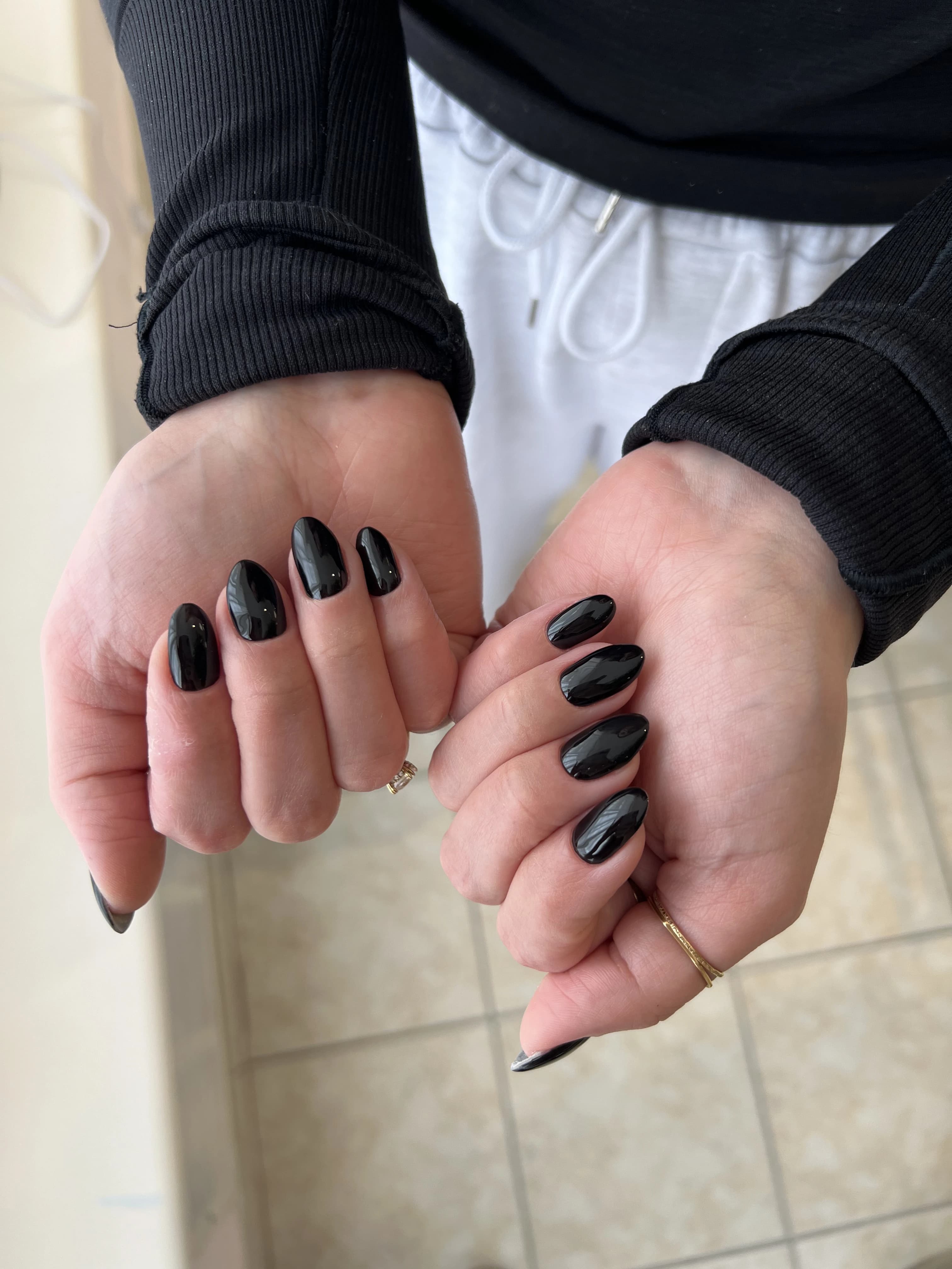 Mirror-gloss jet-black hard gel on oval nails with gold rings, a sleek manicure done at My Beauty Space in Mississauga.