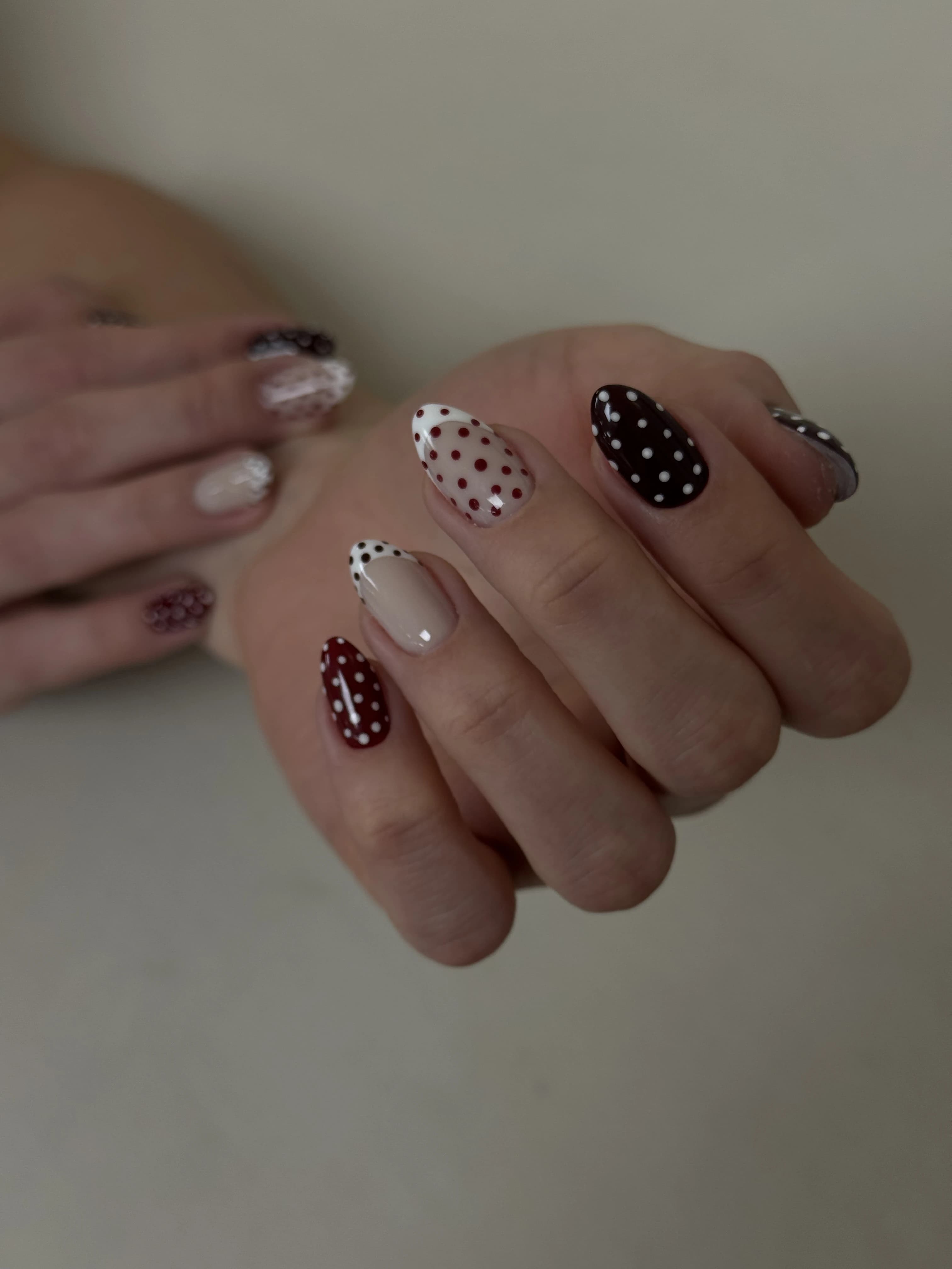 Maroon and white polka-dot nail design at My Beauty Space on almond nails mixing French tips and dotted patterns.