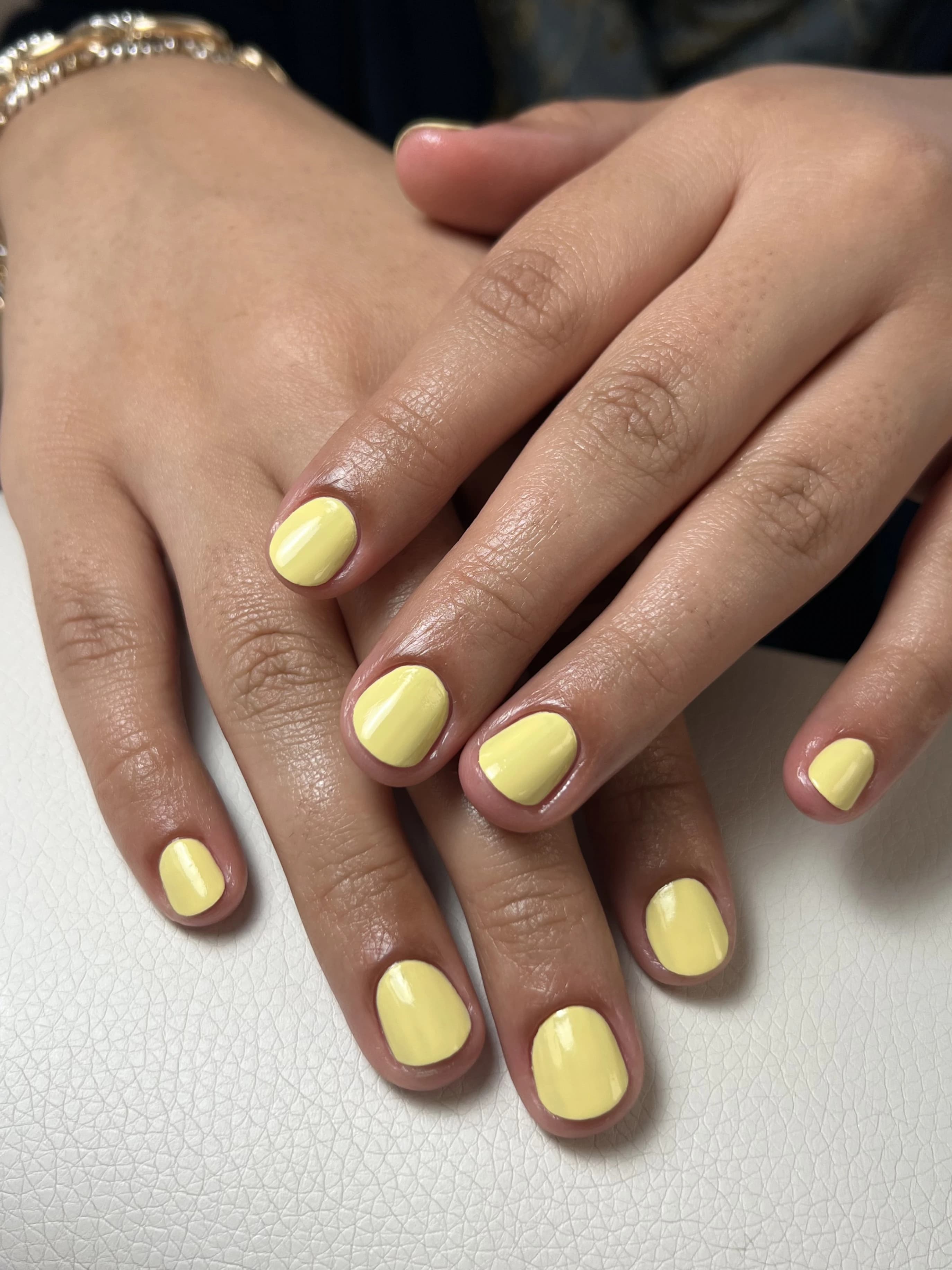 Sunny pastel-yellow regular polish on short rounded nails against white, a fresh manicure at My Beauty Space Mississauga.