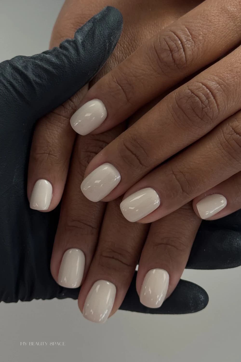 Creamy off-white gel polish on squoval nails held by a gloved technician during a My Beauty Space manicure in Mississauga.
