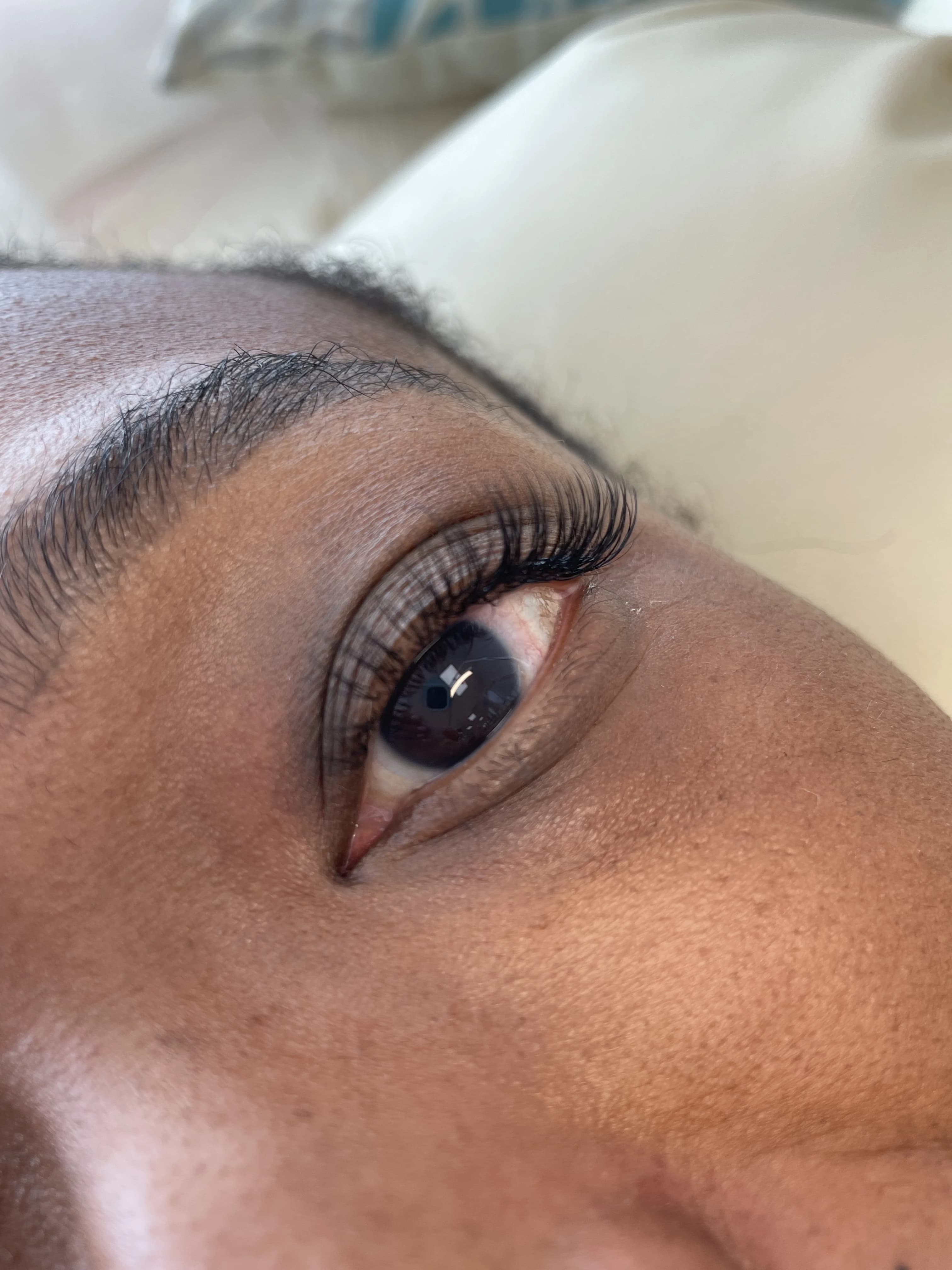 Soft fluttery classic lash extensions on medium skin tone, lying on a salon bed at My Beauty Space Mississauga.